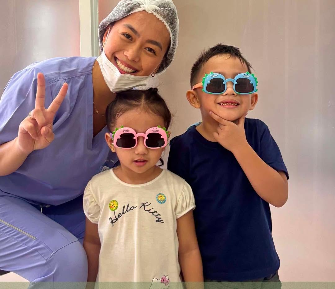 Three young patients wearing playful sunglasses smiling with their dentist