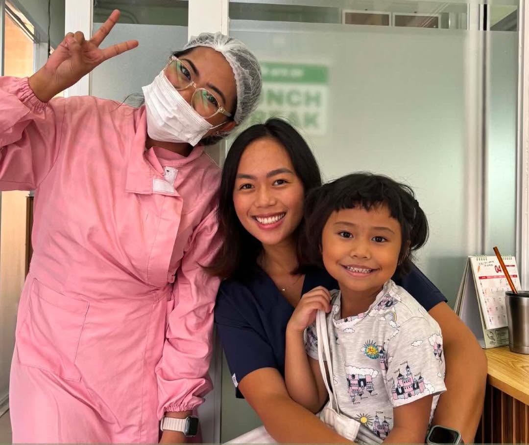 Two Denta Cure staff smiling with a young patient after her check-up
