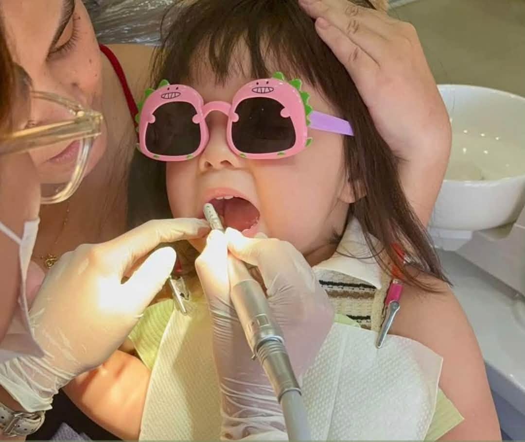 A dentist carefully treating a young patient at Denta Cure Dental Clinic